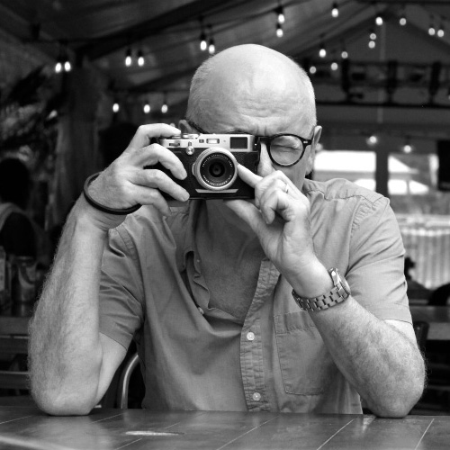 This is a Black and White image shows Simon Thomas pointing his camera at us, the viewer.